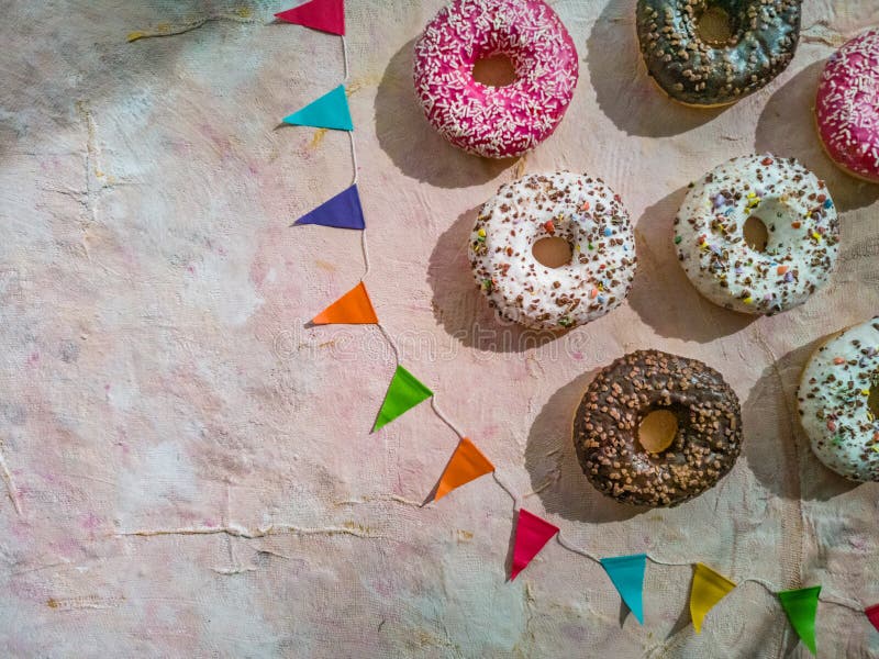 Flat lay of colorful donuts with colorful triangles on light fabric background royalty free stock photography Flat lay of colorful donuts with colorful triangles on light fabric background royalty free stock photography
