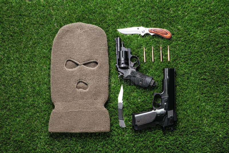 Flat Lay Composition with Balaclava and Weapons on Green Grass Stock