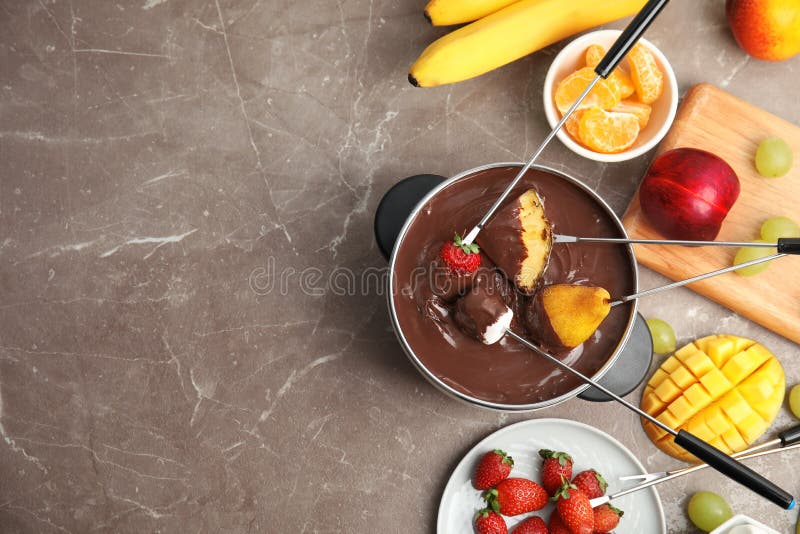 Flat lay composition with chocolate fondue in pot, fruits and space for text
