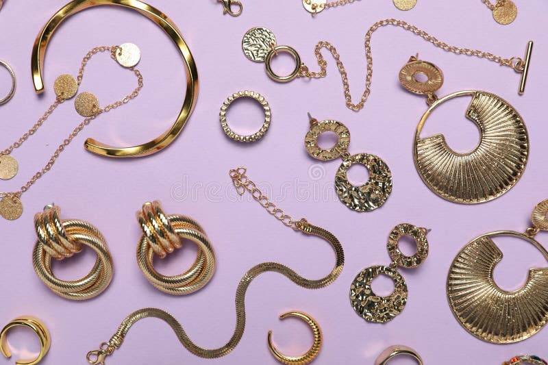 Flat lay composition with golden jewelry on violet background stock photography