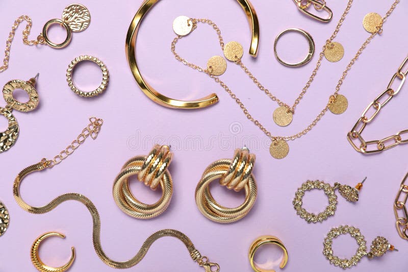 Flat lay composition with golden jewelry on violet background stock photos