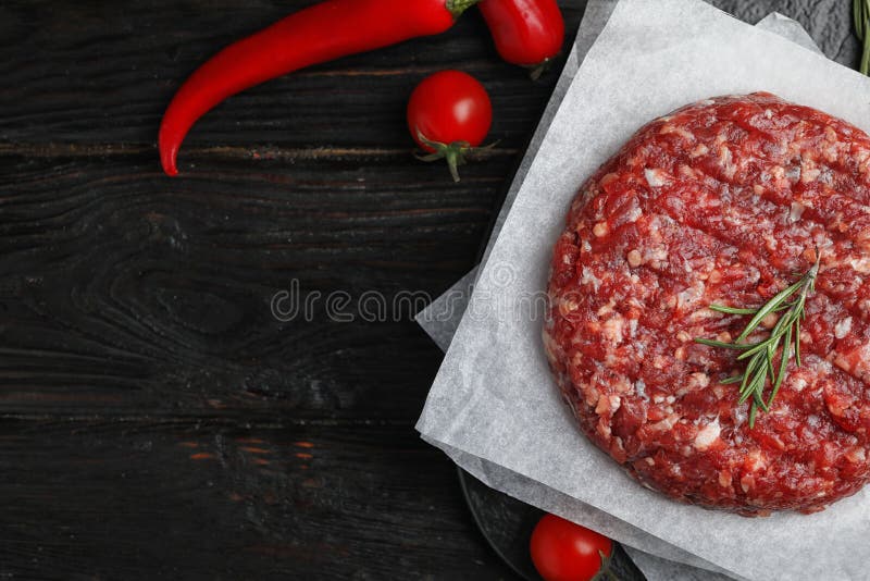 Flat lay composition with raw meat cutlet for burger on wooden table. Space for text