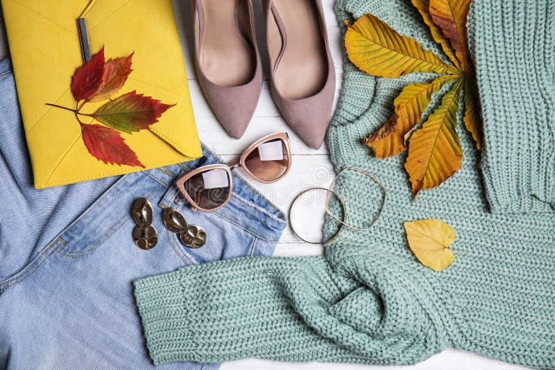 Flat lay composition with warm clothes and autumn leaves on wooden background