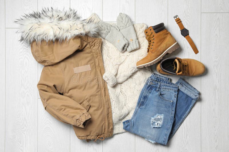 Flat lay composition with winter clothes and boots on wooden background