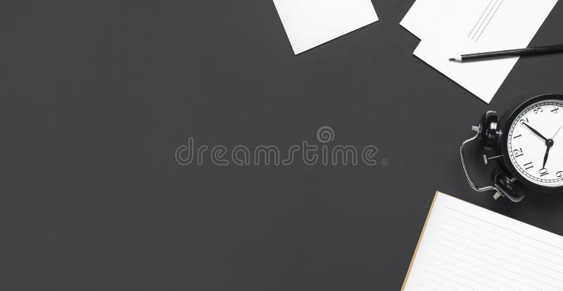 Flat lay cup of black coffee black alarm clock open notebook pencil white cards on gray dark background top view copy space Minimalistic food concept morning breakfast time to work hot drink coffee.