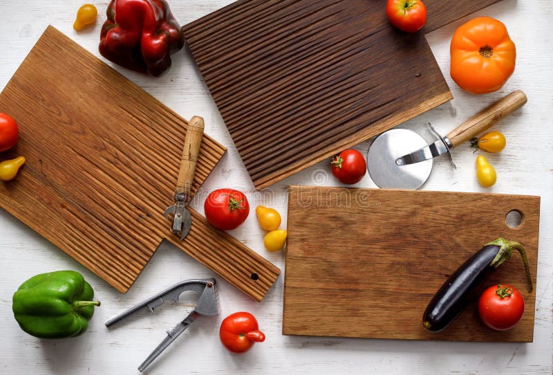 Flat Lay of Dark Oak Cutting Boards, Kitchen Tools and Raw Organic Vegetables on White