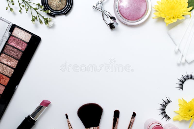 Flat lay of decorative cosmetics with makeup brushes flowers and skincare products frame on white background