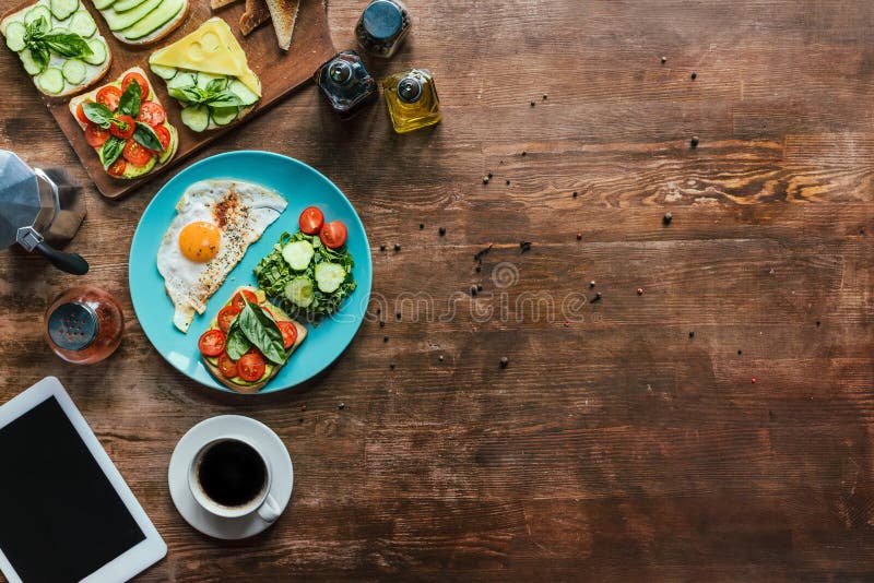 flat lay with healthy breakfast on plate, cup of coffee and tablet