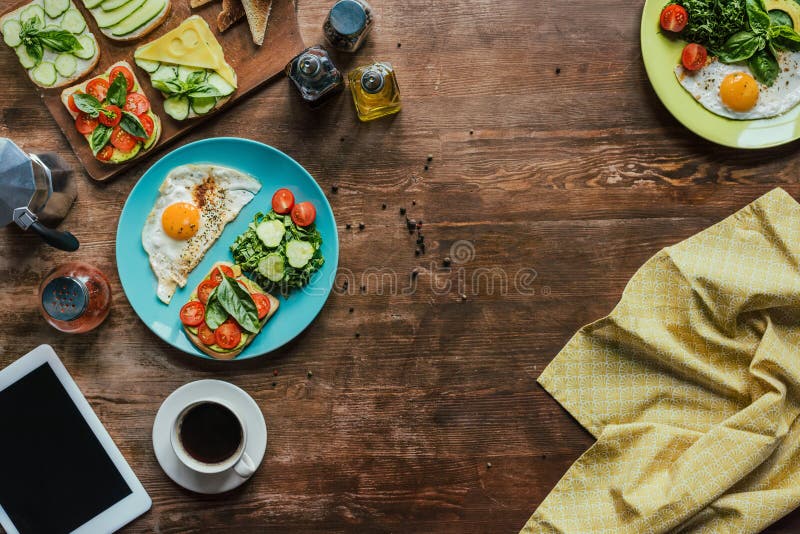 flat lay with healthy breakfast for two with fried eggs, toasts, vegetables and cup of coffee