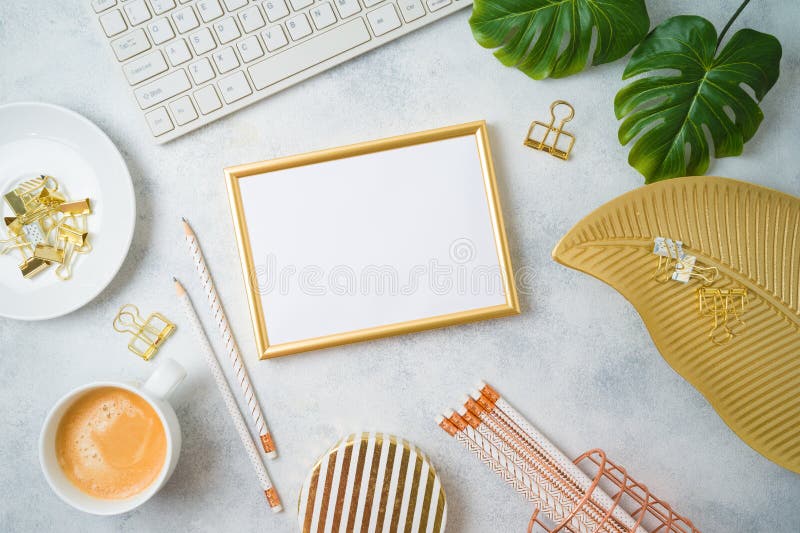 Flat lay home office feminine table with frame mockup, golden accessories, computer keyboard and tropical leaves on grey stock photos Flat lay home office feminine table with frame mockup, golden accessories, computer keyboard and tropical leaves on grey stock photos