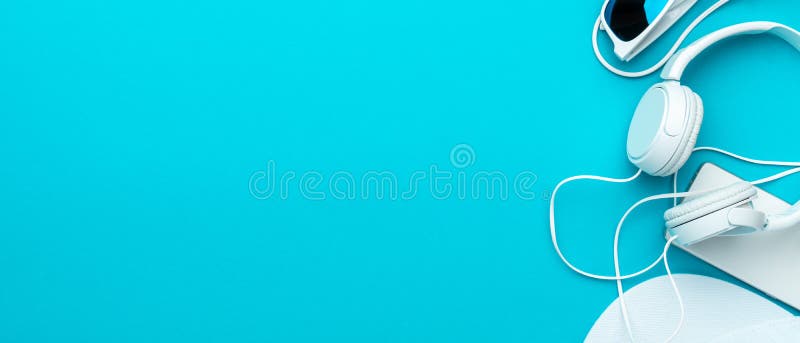 Flat lay image of modern teenager accessories background - headphones, sunglasses, smartphone, baseball cap. Top view of white accessories on turquoise blue background with copy space. Flat lay image of modern teenager accessories background - headphones, sunglasses, smartphone, baseball cap. Top view of white accessories on turquoise blue background with copy space