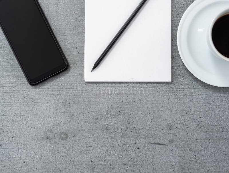 Flat lay of office space with a view of a smartphone, notepad with a pencil and a cup of coffee royalty free stock photo