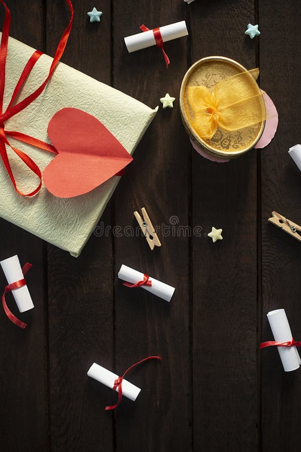 Flat lay romantic background. Gift box with rolled wishes paper gift pack on wooden board stock photo Flat lay romantic background. Gift box with rolled wishes paper gift pack on wooden board stock photo