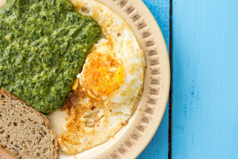 Flat lay spinach with fried eggs and slice of black bread stock photography Flat lay spinach with fried eggs and slice of black bread stock photography