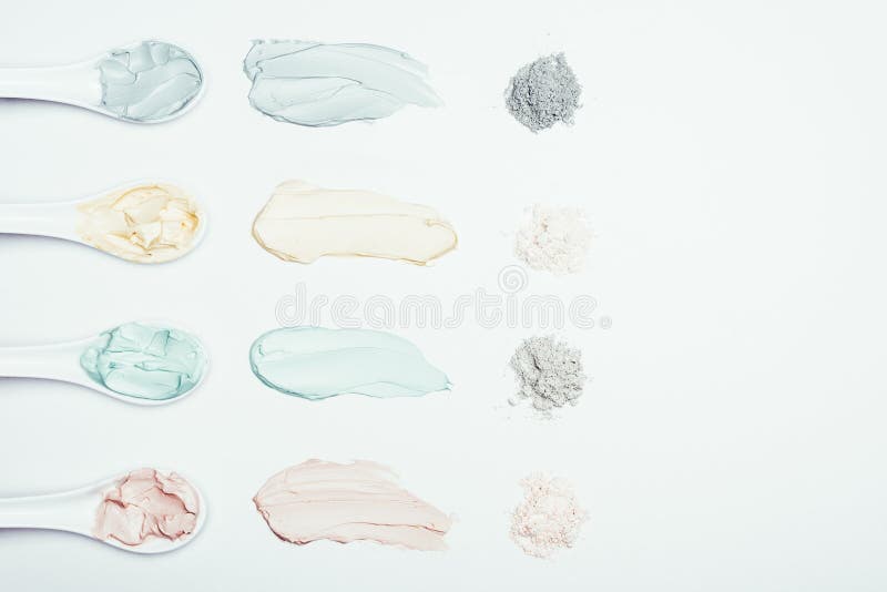 flat lay with spoons, clay powder and colorful clay mask smudges placed in row