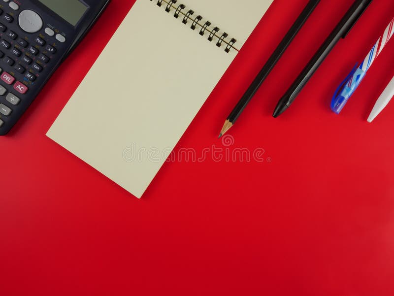 Flat lay stationery with notebook and calculator on red background with copy space stock images