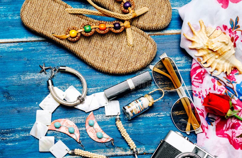 Flat lay of summer fashion with camera slippers sunglasses and other girl accessories on blue background