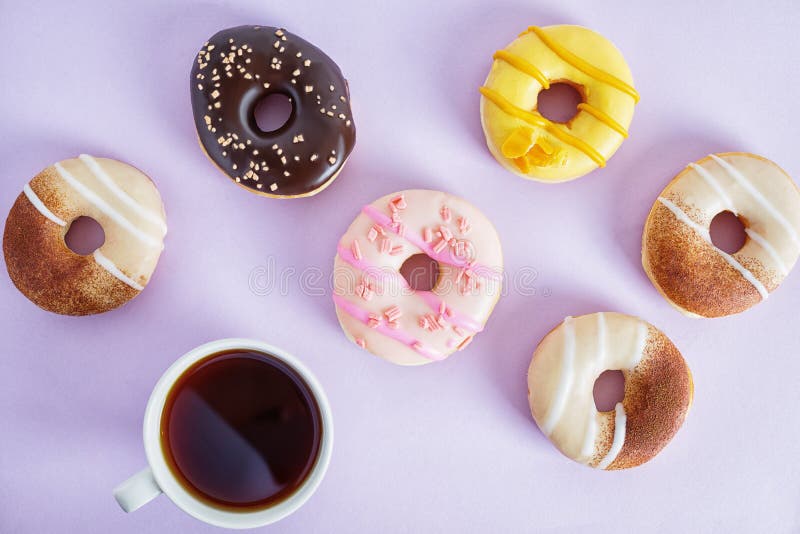 Flat lay top view colorful donuts on bright purple paper. Creative food decor background. Junk food