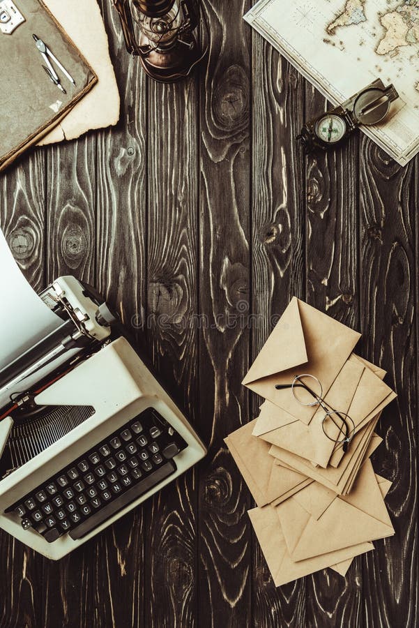 flat lay with typing machine, map, compass, eyeglasses and blank envelopes on dark