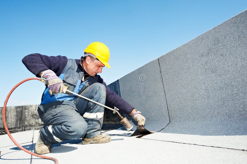 Roofer installazione di Coperture in feltro con riscaldamento e la fusione rotolo di bitume rotolo da torcia in fiamme.