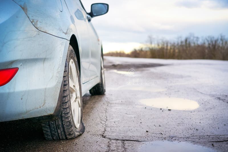 Flat tire of blue car on the road waiting for repair. Car tire leak because of nail pounding royalty free stock images Flat tire of blue car on the road waiting for repair. Car tire leak because of nail pounding royalty free stock images