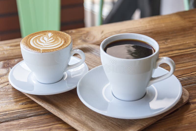 Flat white or cappuccino with coffee art and filter coffee in white cups on wooden table. Different coffee styles, morning drink in cafe on small wooden tray. Different color styles stock images, royalty-free photos and pictures
