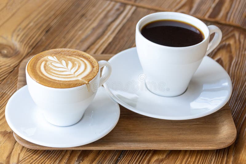 Flat white or cappuccino with coffee art and filter coffee in white cups on wooden table. Different coffee styles, morning drink in cafe on small wooden tray. Different color styles stock images, royalty-free photos and pictures