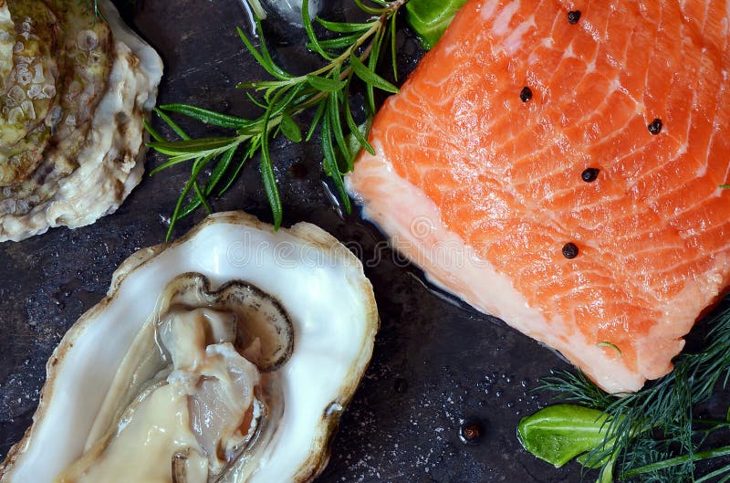 flatlay Composizione di frutti di mare freschi su un fondo scuro Trota ed ostriche con le erbe ed il limone immagine stock flatlay Composizione di frutti di mare freschi su un fondo scuro Trota ed ostriche con le erbe ed il limone immagine stock