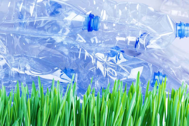 Flattened plastic bottles ready for recycling on green grass. Plastic pollution stock image