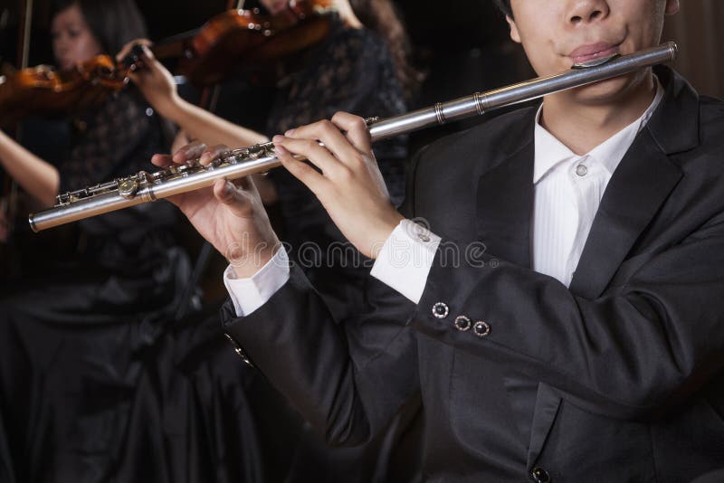 Flautist holding and playing the flute during a performance, close-up royalty free stock photography