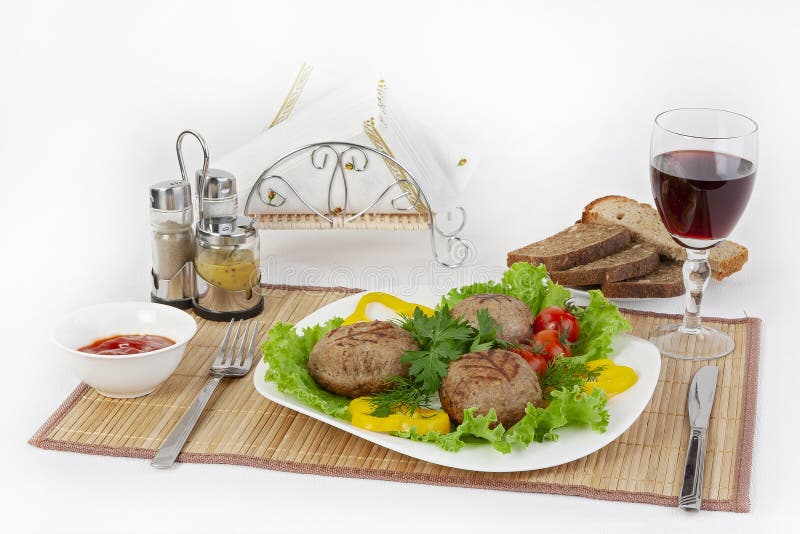 Fleisch des Rindfleisches, rundes rhizol Runde Fleischkoteletts mit Grüns, Tomaten und einem Glas Wein Nützliches und geschmackvo stockbild Fleisch des Rindfleisches, rundes rhizol Runde Fleischkoteletts mit Grüns, Tomaten und einem Glas Wein Nützliches und geschmackvo stockbild