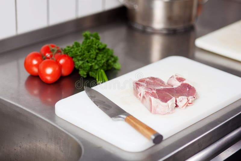 Closeup of meat piece and knife on chopping board in commercial kitchen. Closeup of meat piece and knife on chopping board in commercial kitchen