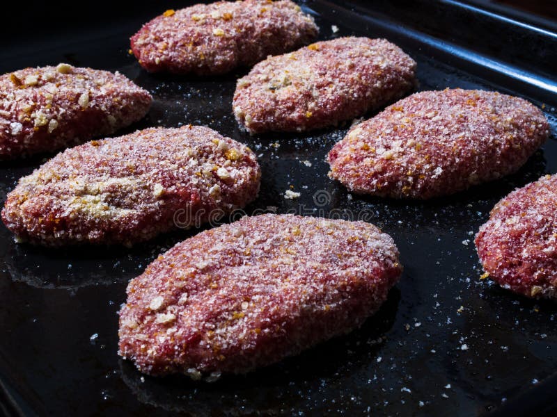 Fleischpastetchenhalbzeuge, besprüht mit den Brotkrumen, ordentlich verbreitet auf einem Backblech bevor dem Kochen im Ofen lizenzfreie stockfotografie Fleischpastetchenhalbzeuge, besprüht mit den Brotkrumen, ordentlich verbreitet auf einem Backblech bevor dem Kochen im Ofen lizenzfreie stockfotografie