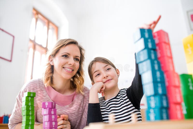 Fleißige Lehrerin lernt mit jungen Schülerinnen im Klassenzimmer, indem sie ihre Brüche mithilfe von Schulwerkzeugen erklärt. lizenzfreies stockfoto
