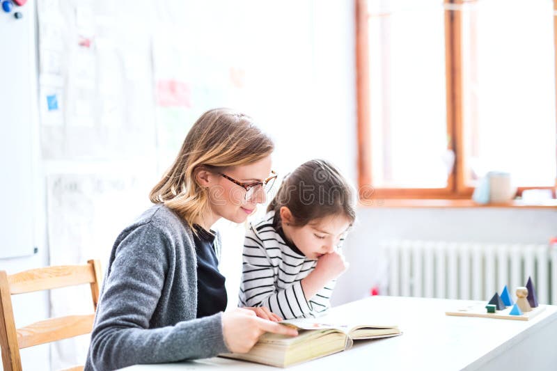 Fleißiger Lehrer, der mit einer jungen Schülerin im Klassenzimmer lernt und dabei hilft, Probleme beim Lesen zu lösen. Dyslexie. e stockbild