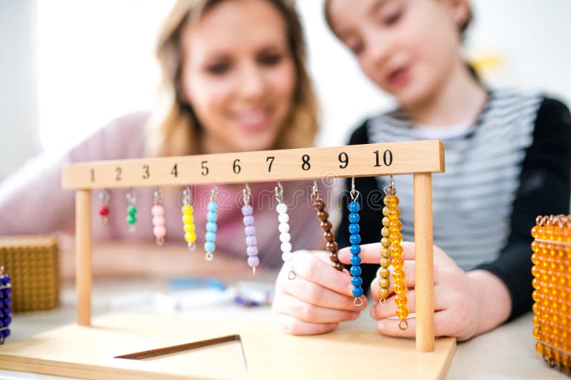 Fleißiger Lehrer, der mit jungen Schülerinnen im Klassenzimmer lernt und Mathematik mithilfe von Lehrmitteln erklärt. lizenzfreie stockbilder