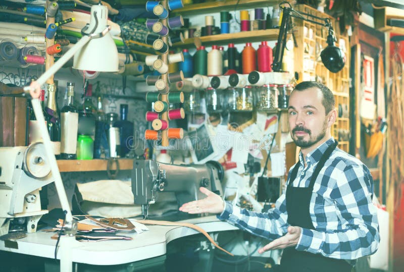 Fleißiger Mann, der seine Werkzeuge in der ledernen Werkstatt zeigt stockfotografie Fleißiger Mann, der seine Werkzeuge in der ledernen Werkstatt zeigt stockfotografie