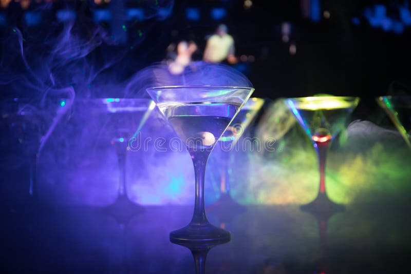 Flera exponeringsglas av den berömda coctailen Martini, skott på en stång med mörker tonade dimmiga bakgrunds- och diskoljus Klub royaltyfri bild Flera exponeringsglas av den berömda coctailen Martini, skott på en stång med mörker tonade dimmiga bakgrunds- och diskoljus Klub royaltyfri bild