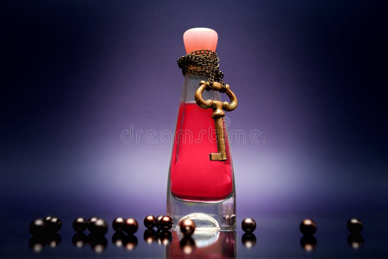 Fles van blauw liefdedrankje met ketting en sleutel rond de fles royalty-vrije stock afbeeldingen Fles van blauw liefdedrankje met ketting en sleutel rond de fles royalty-vrije stock afbeeldingen
