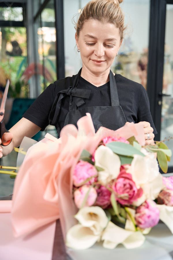 Fleuriste joyeuse tenant des ciseaux et regardant bouquet fini photos stock