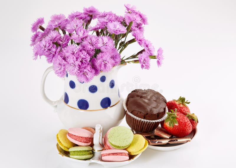 Fleurs dans le vase avec des macarons sur la soucoupe Oeillets et bonbons photographie stock libre de droits Fleurs dans le vase avec des macarons sur la soucoupe Oeillets et bonbons photographie stock libre de droits