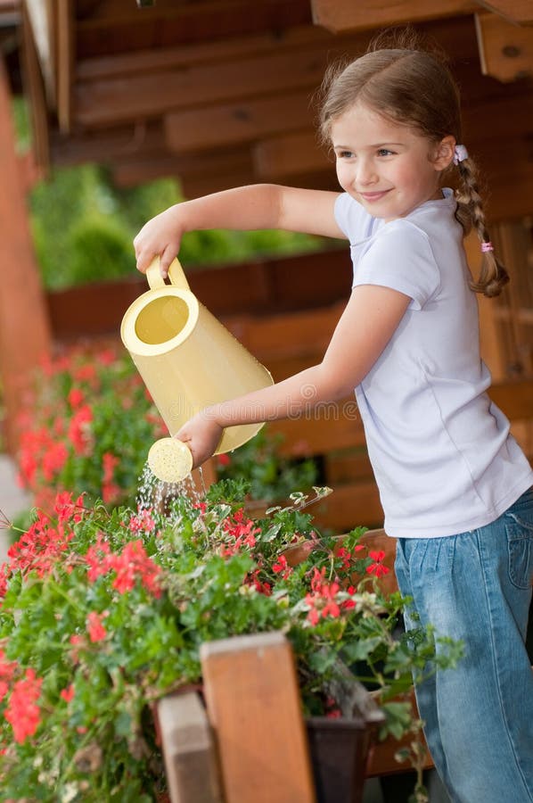 Fleurs de arrosage de petite fille photo stock Fleurs de arrosage de petite fille photo stock
