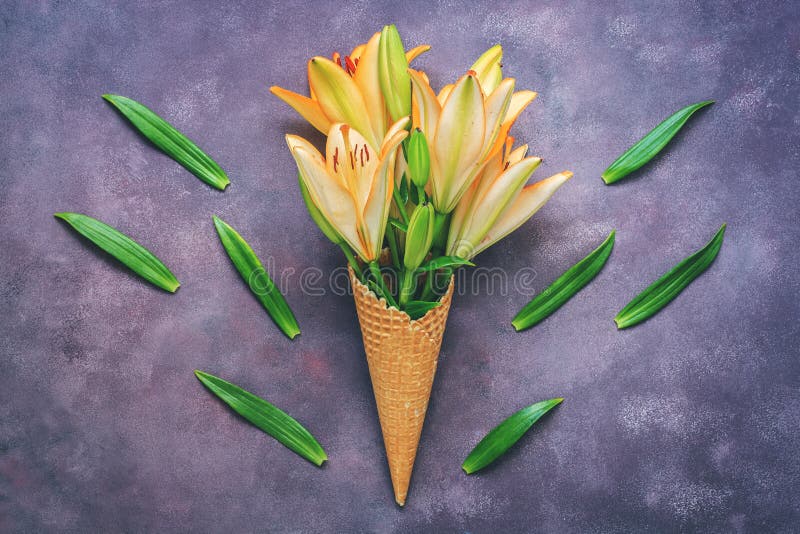 Fleurs jaunes de lis dans un cône de gaufre sur un beau fond multicolore abstrait Composition élégante Modèle des feuilles vertes image libre de droits Fleurs jaunes de lis dans un cône de gaufre sur un beau fond multicolore abstrait Composition élégante Modèle des feuilles vertes image libre de droits