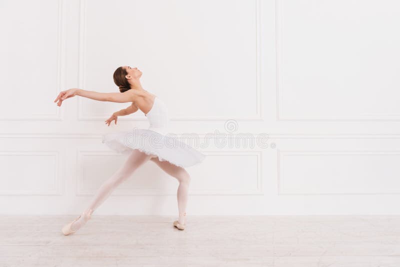 Try to do it. Tender girl holding her left leg bent in knee keeping both arms in the air while looking upwards. Try to do it. Tender girl holding her left leg bent in knee keeping both arms in the air while looking upwards