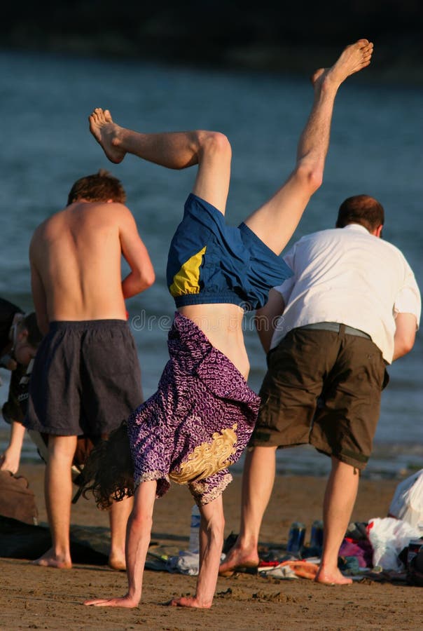 Adolescente sulla spiaggia, facendo una verticale con i suoi amici accanto a lui.