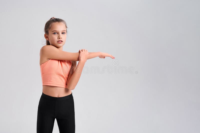 I play fitness. Flexible cute little girl child looking at camera while doing exercise isolated on a white background