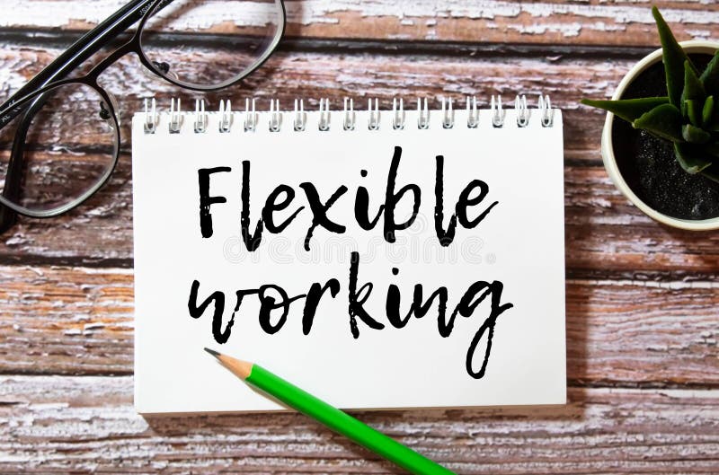 FLEXIBLE WORKING text on notebook with pen and table lamp on black background. stock image