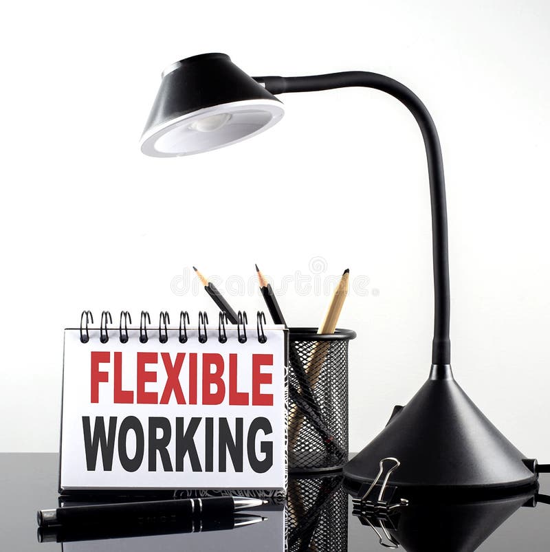 FLEXIBLE WORKING text on notebook with pen and table lamp on the black background royalty free stock photography