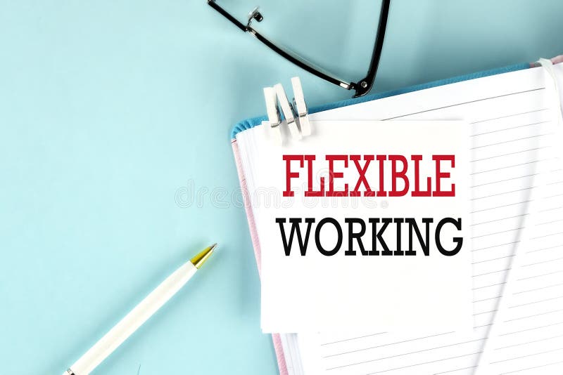 FLEXIBLE WORKING text on a sticky on notebook with pen and glasses , blue background