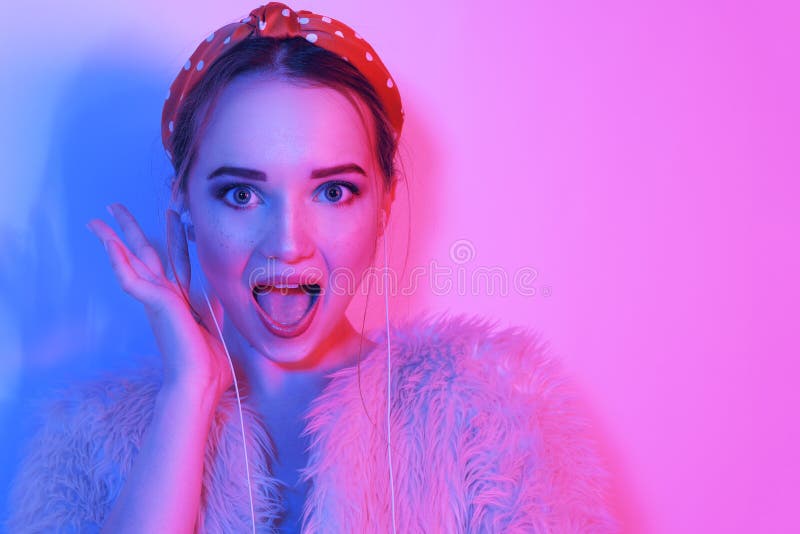 Flicka i h?rlurar som lyssnar till musik De flickaleendena och skratten Modestående av den unga eleganta flickan i ett rosa lag o arkivfoto Flicka i h?rlurar som lyssnar till musik De flickaleendena och skratten Modestående av den unga eleganta flickan i ett rosa lag o arkivfoto